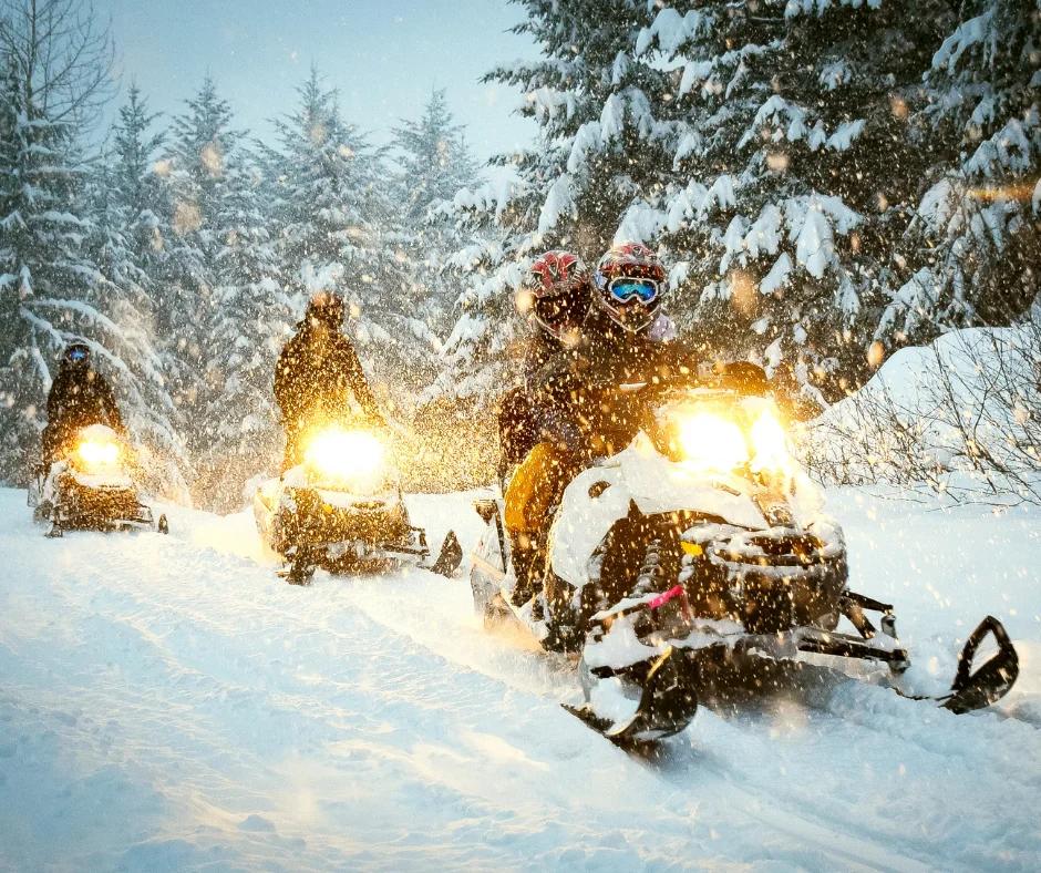 three people snowmobiling