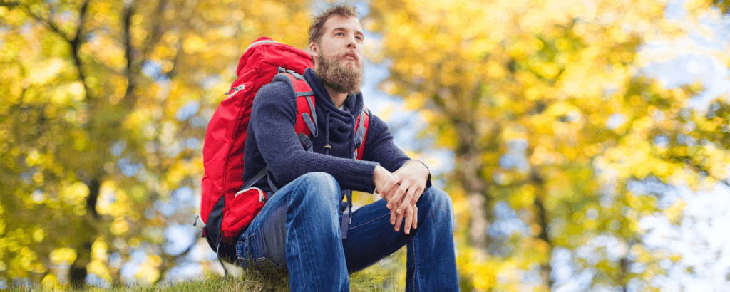 solo man sitting on a rock feature with a hiking backpack