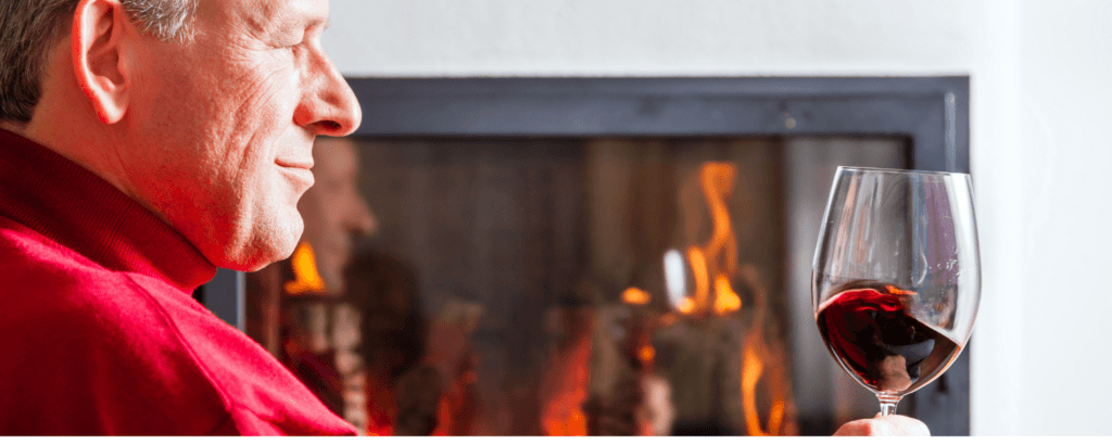 Solo man enjoying drinking wine by a fire in a hearth