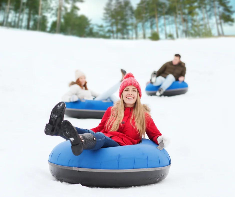 people dressed for winter snow tubing down a hill