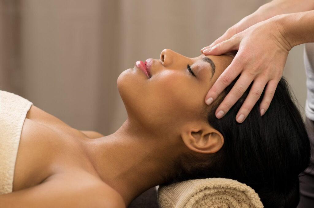 Closeup of young woman receiving professional head massage at spa