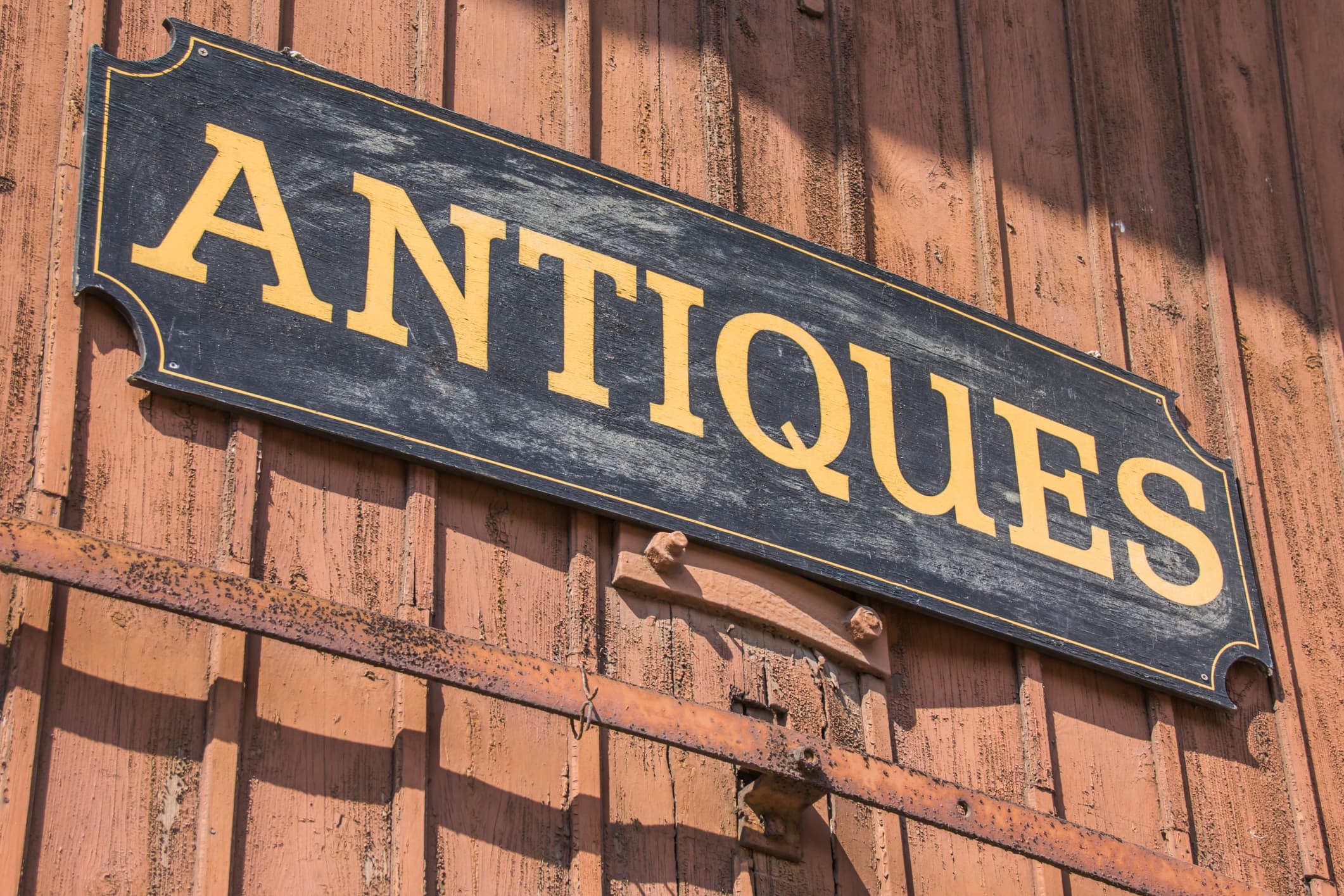 A weathered sign reading "ANTIQUE" against a rustic wooden background. A weathered sign reading "ANTIQUE" against a rustic wooden background.