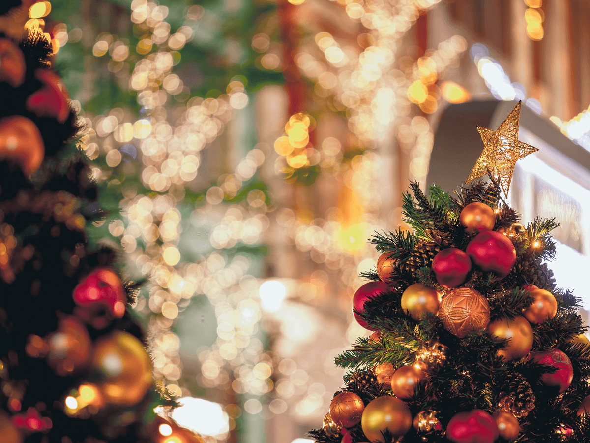 Close-up of a decorated Christmas tree with a star on top and blurred festive lights in the background. Close-up of a decorated Christmas tree with a star on top and blurred festive lights in the background.