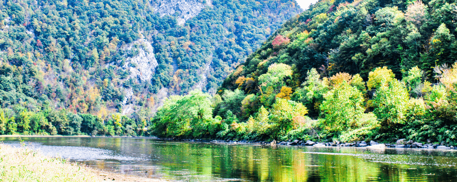 A serene river surrounded by lush, colorful trees and mountains.