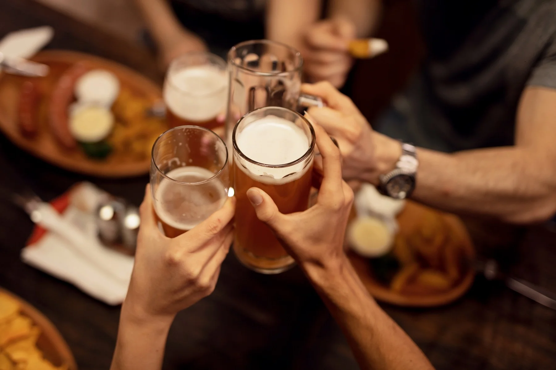 A group of friends clinking glasses of beer at a table.