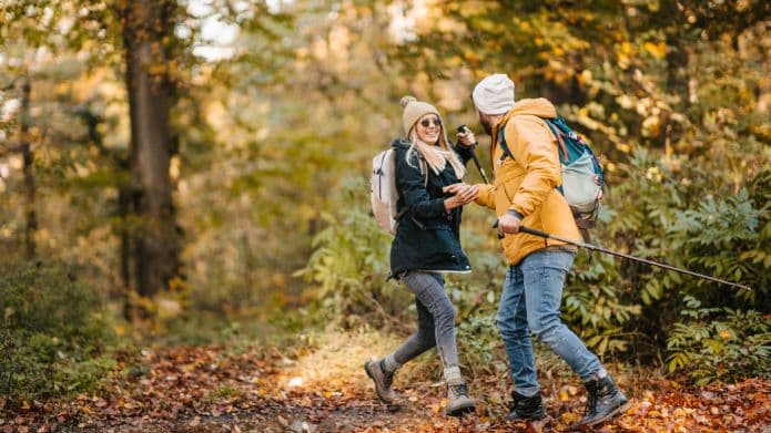 Two hikers share a joyful moment on a scenic forest trail during autumn. Two hikers share a joyful moment on a scenic forest trail during autumn.