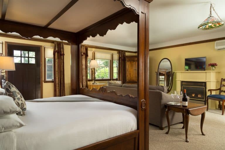 Cozy room featuring a four-poster bed, a seating area, and a fireplace.