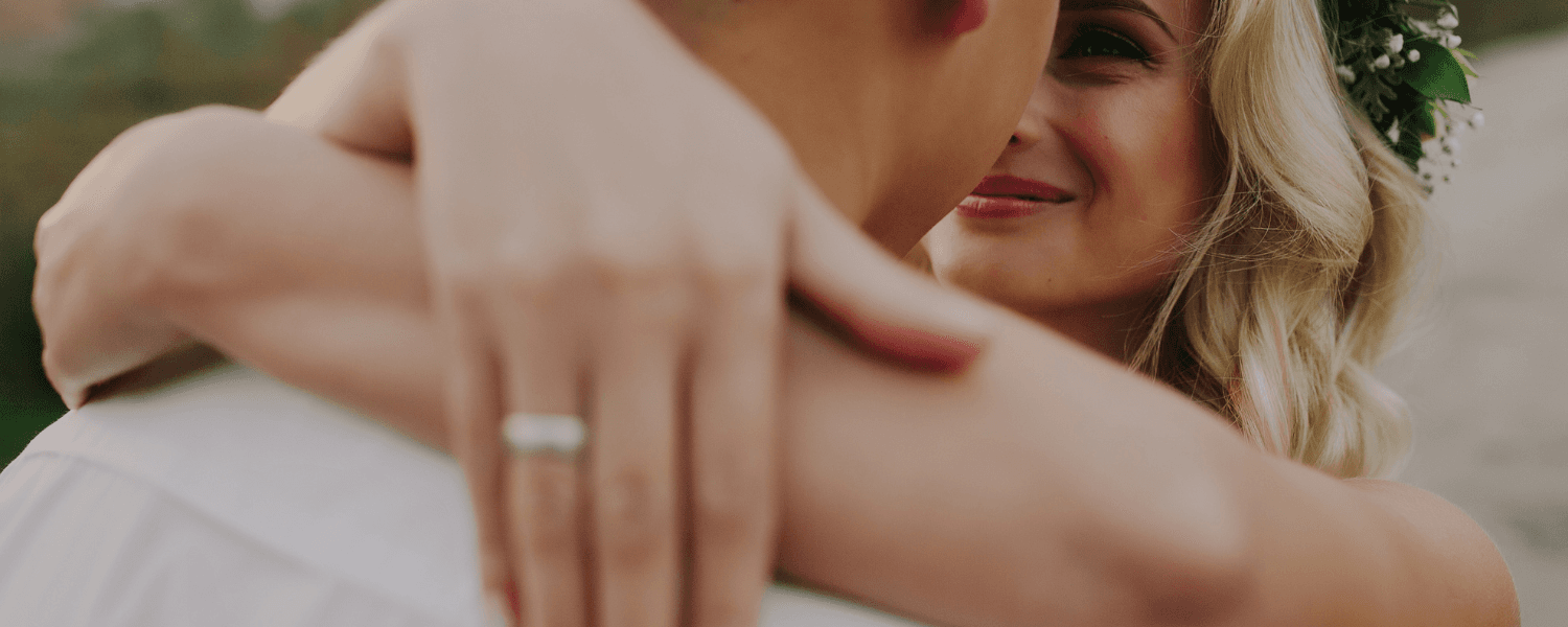 A couple shares a tender embrace, with the bride smiling at her partner. A couple shares a tender embrace, with the bride smiling at her partner.