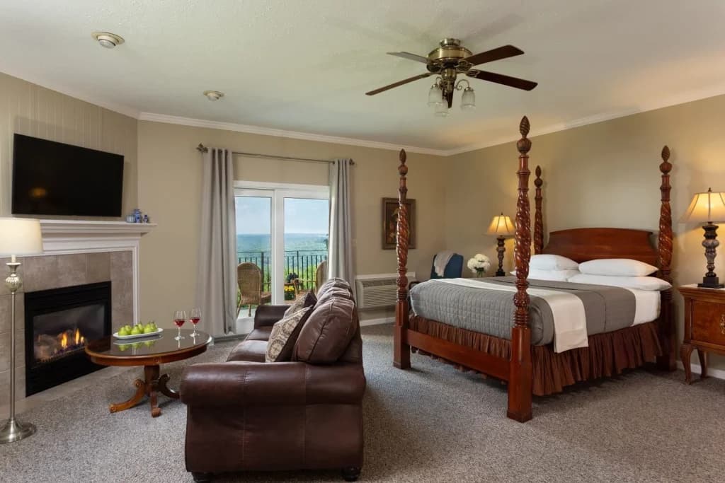 A cozy hotel room featuring a four-poster bed, a seating area, and a scenic view.