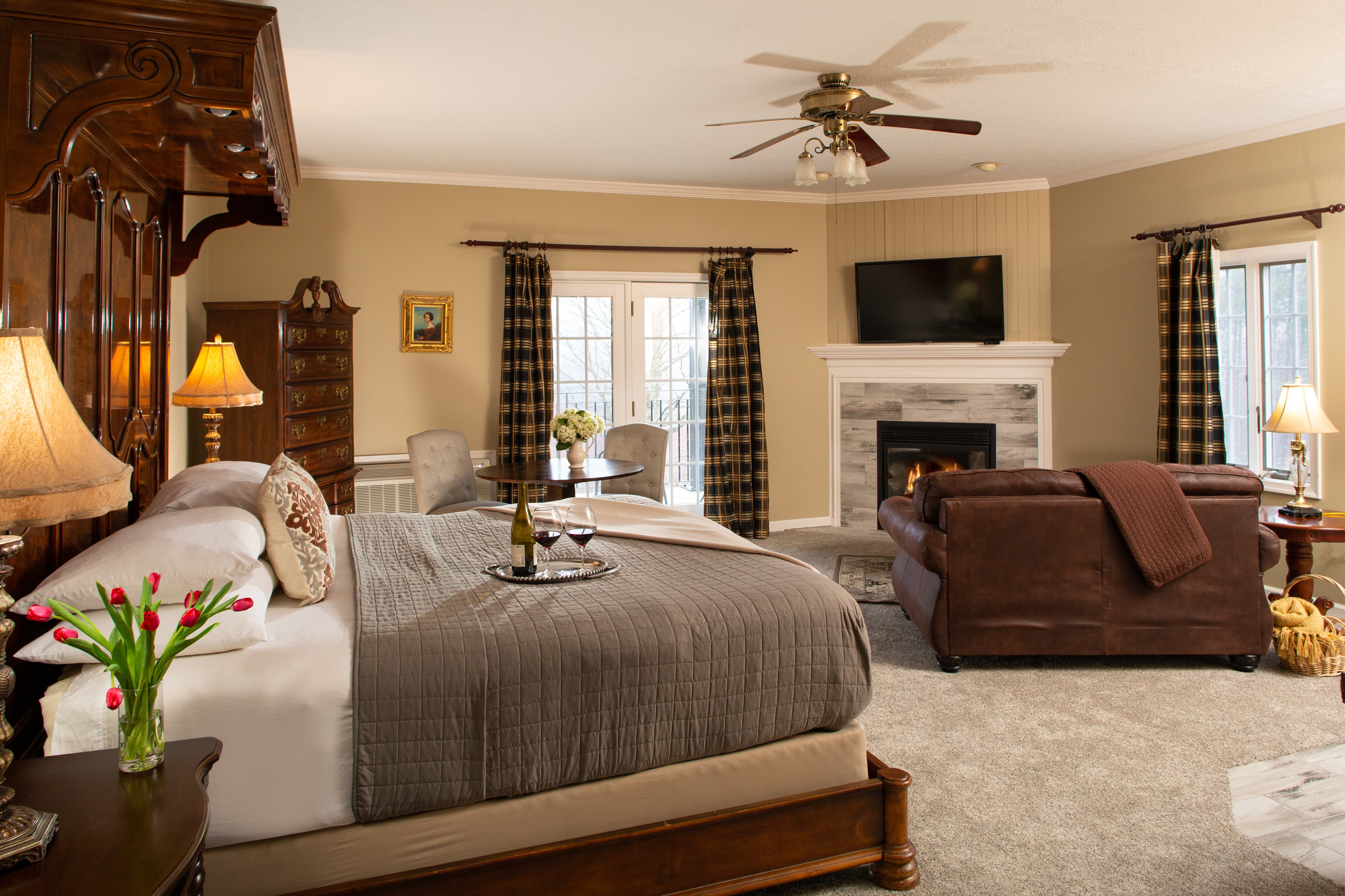 A cozy, elegantly furnished bedroom featuring a king-sized bed, a fireplace, and a seating area.