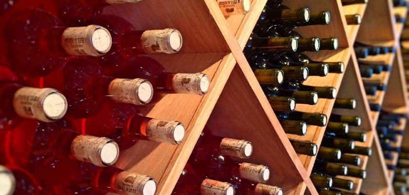 A wooden wine rack displaying bottles of red and white wine with corks visible.