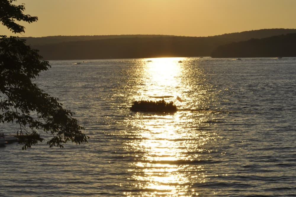 A scenic view of Lake Wallenpaupack at sunset, with several boats out on the water.