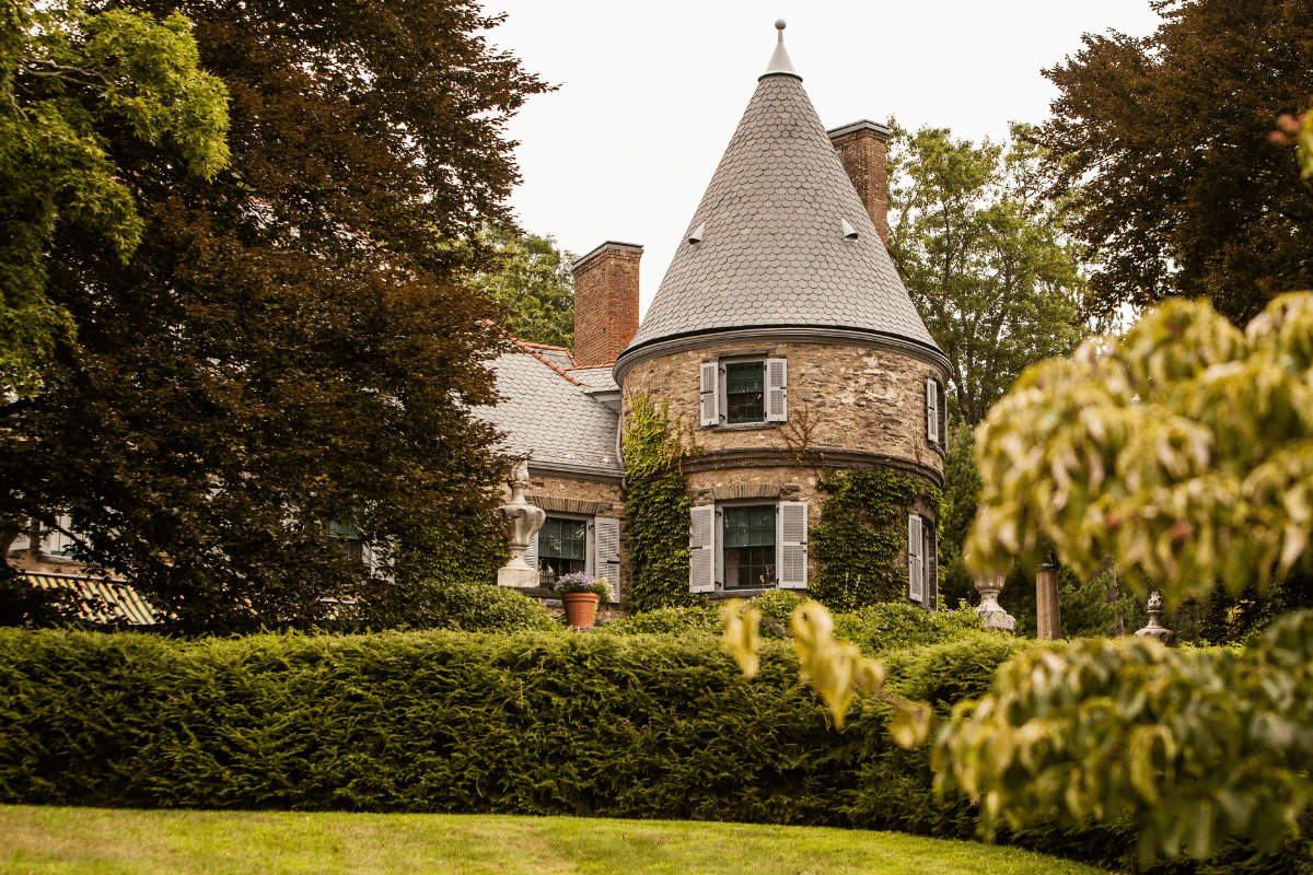 A stone house with a conical roof surrounded by lush greenery.