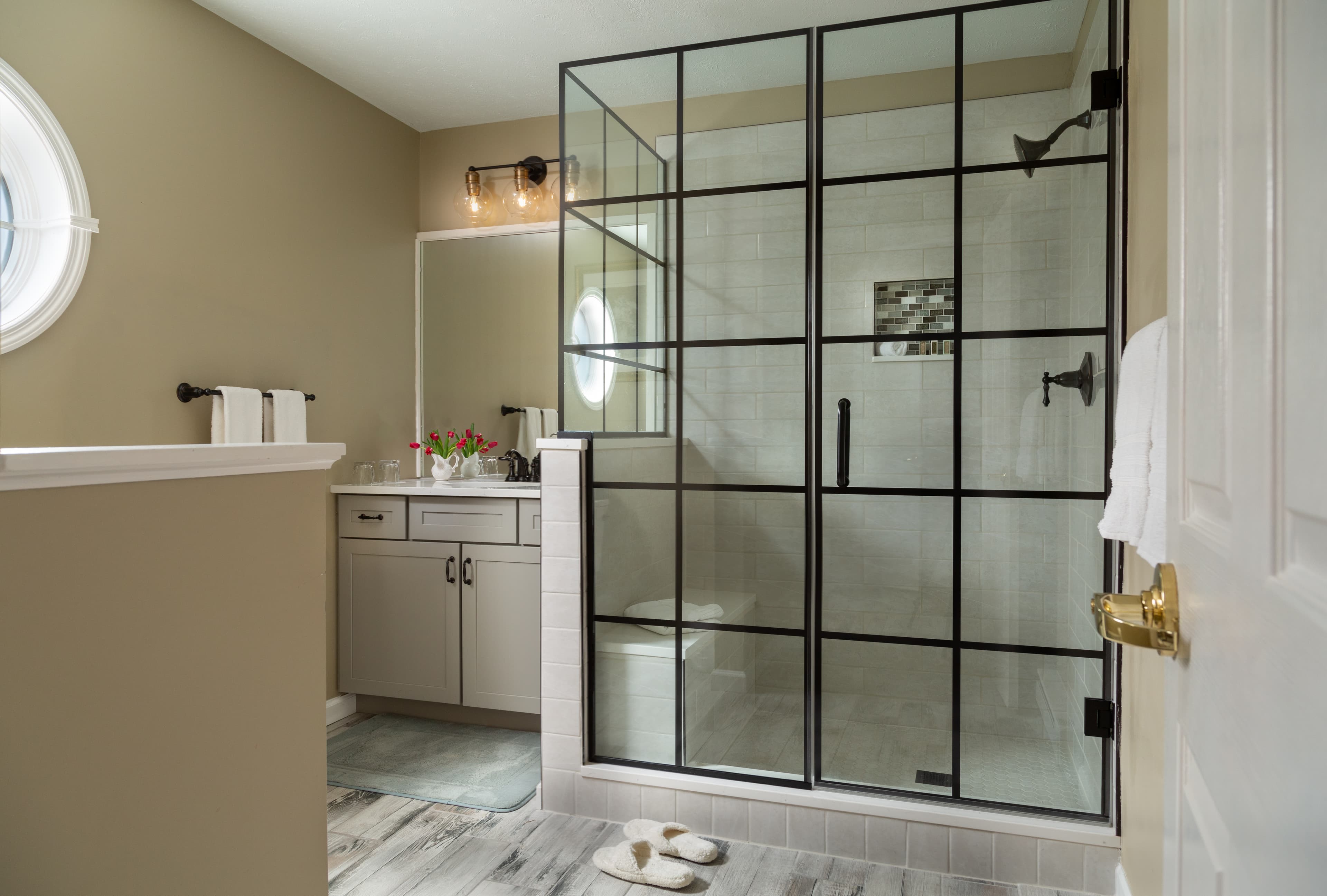 Modern bathroom featuring a glass shower, vanity with flowers, and neutral-toned walls.