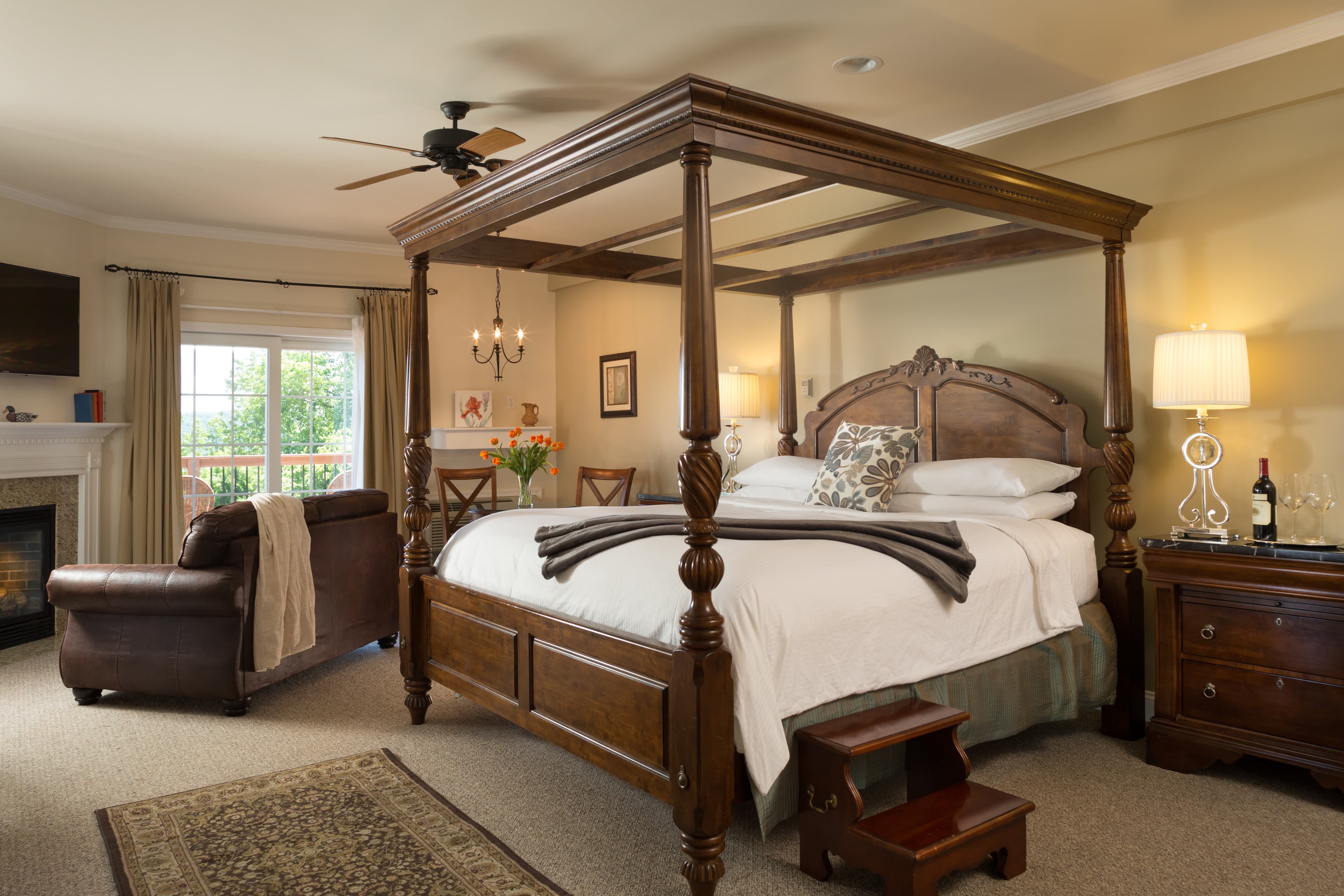 Luxurious bedroom featuring a four-poster bed, armchair, and natural light from large windows.