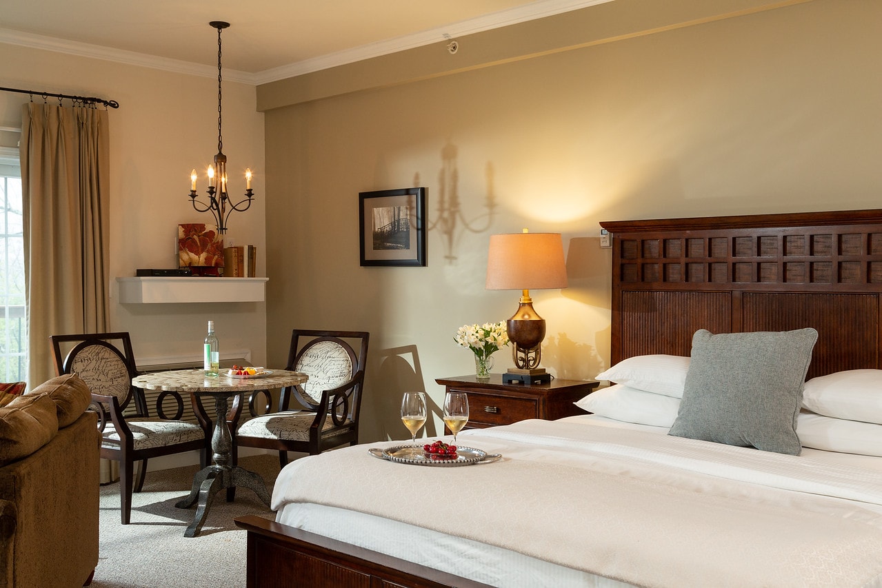 A cozy hotel room featuring a bed, a small dining table, and stylish decor.