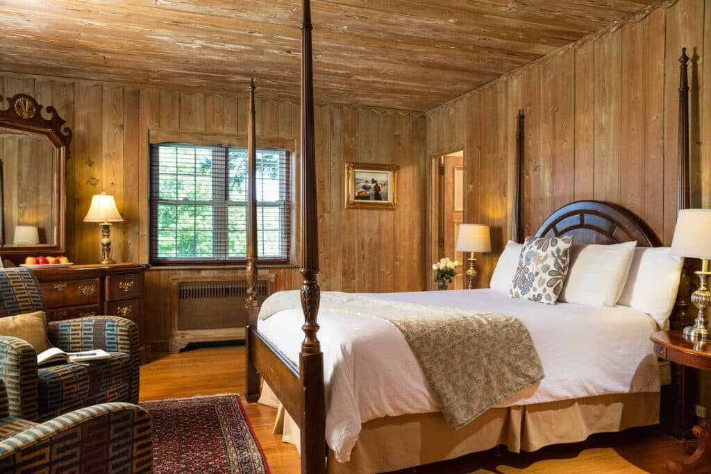 Cozy bedroom with wooden walls, a king-sized bed, and vintage furnishings.