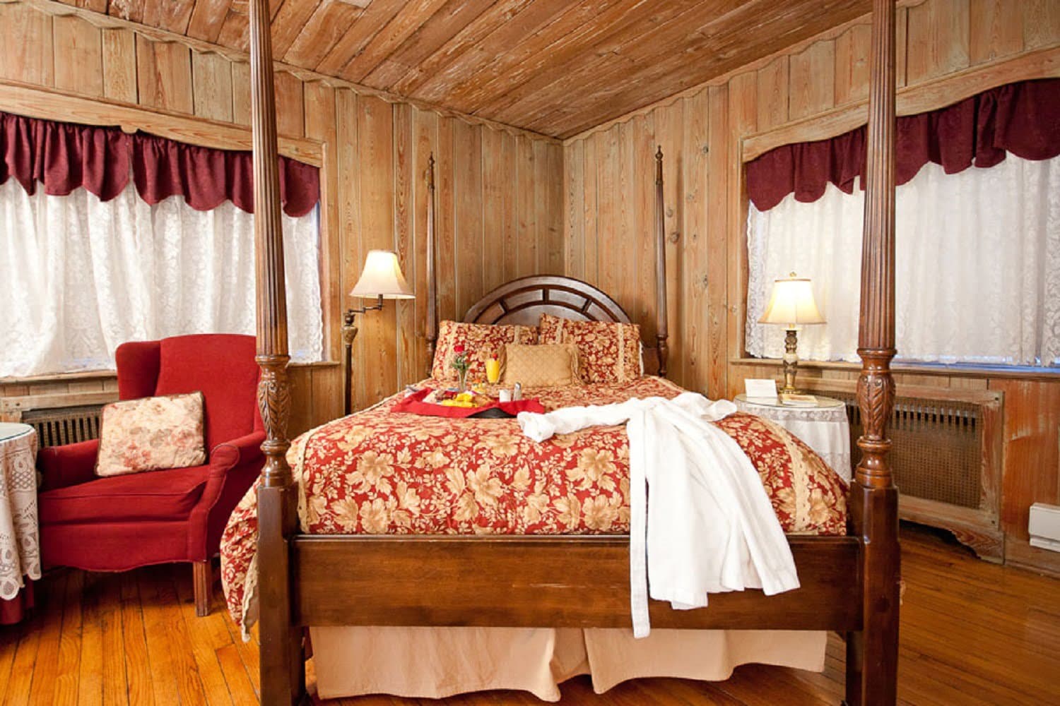 A cozy, rustic bedroom featuring a four-poster bed, floral bedding, and warm wooden accents.