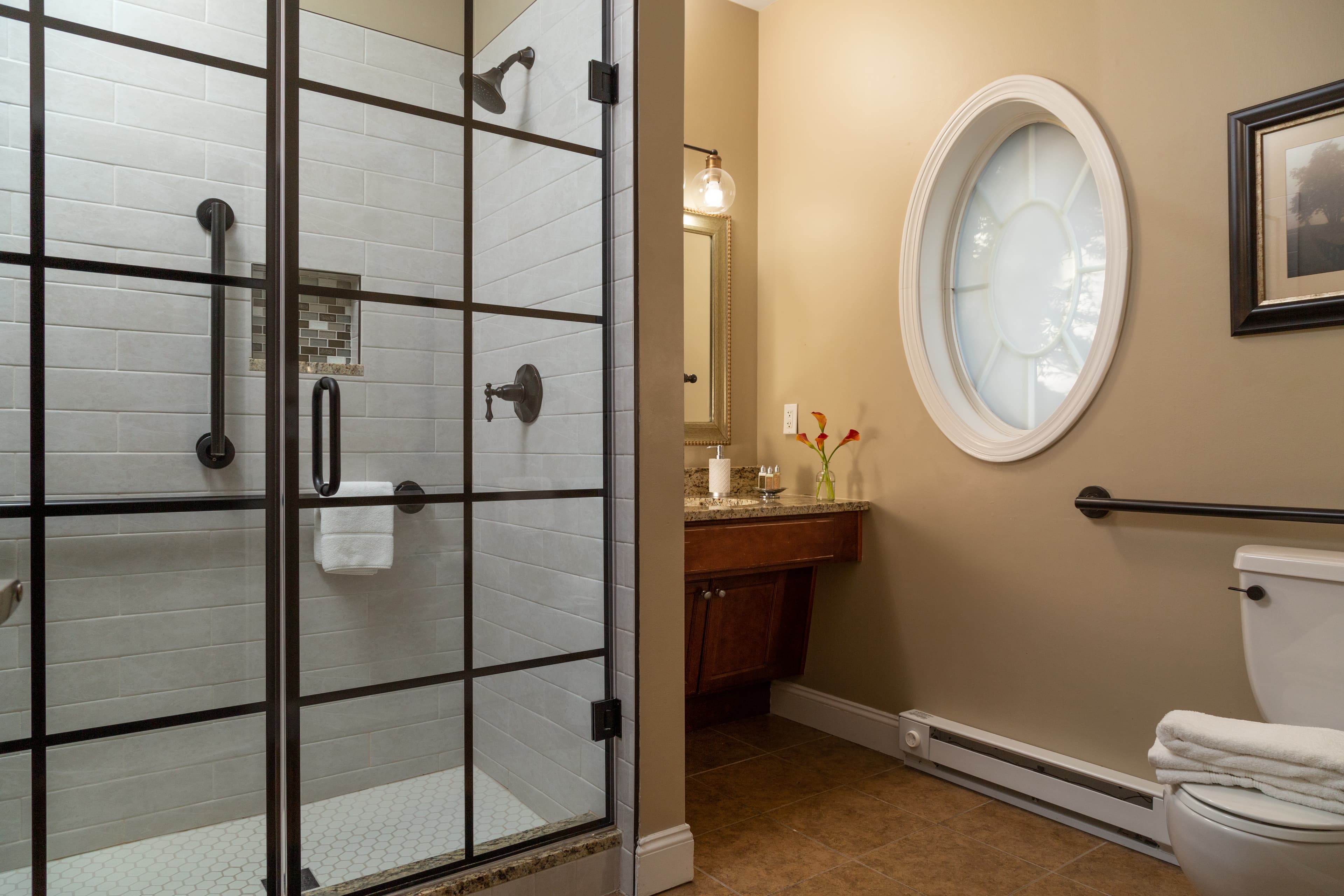 A modern bathroom featuring a glass shower enclosure, a wooden vanity, and decorative elements.