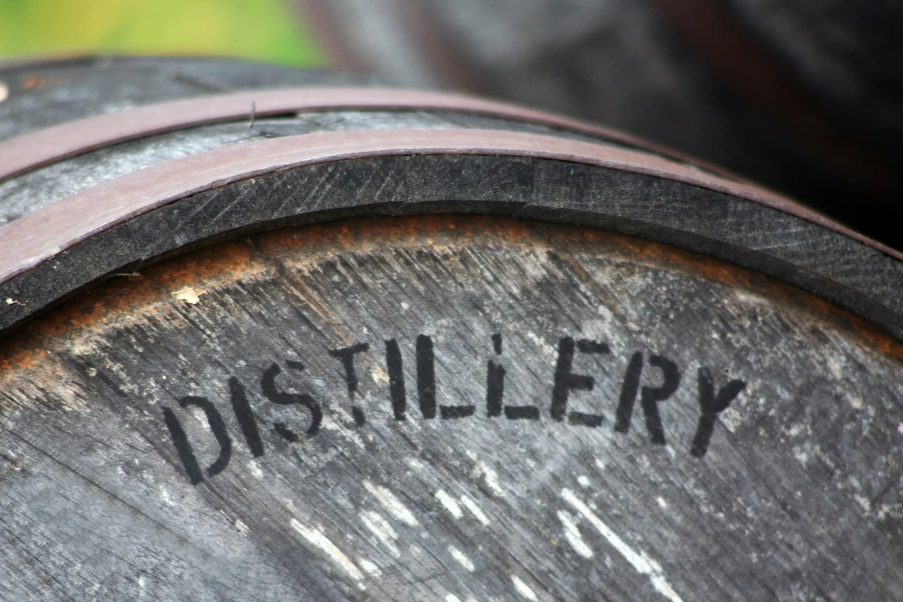 Close-up of a wooden barrel with the word "DISTILLERY" stamped on it.