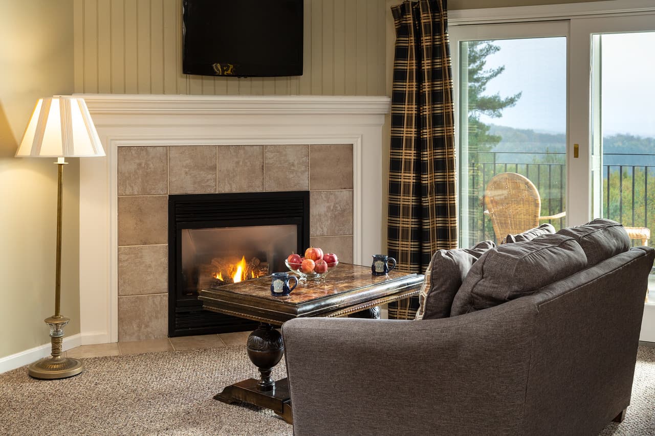 Cozy living room featuring a fireplace, a coffee table with fruit, and a view through sliding glass doors.