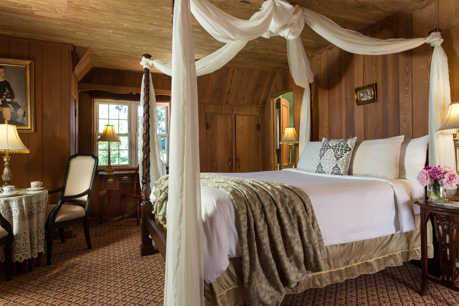 Cozy bedroom with a four-poster bed, wooden walls, and elegant decor.