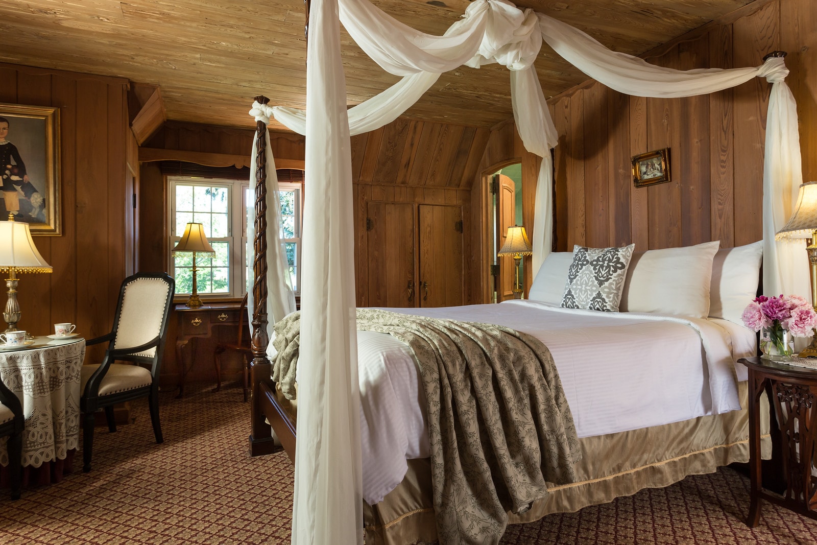 Cozy bedroom with a four-poster bed, wooden walls, and elegant decor.