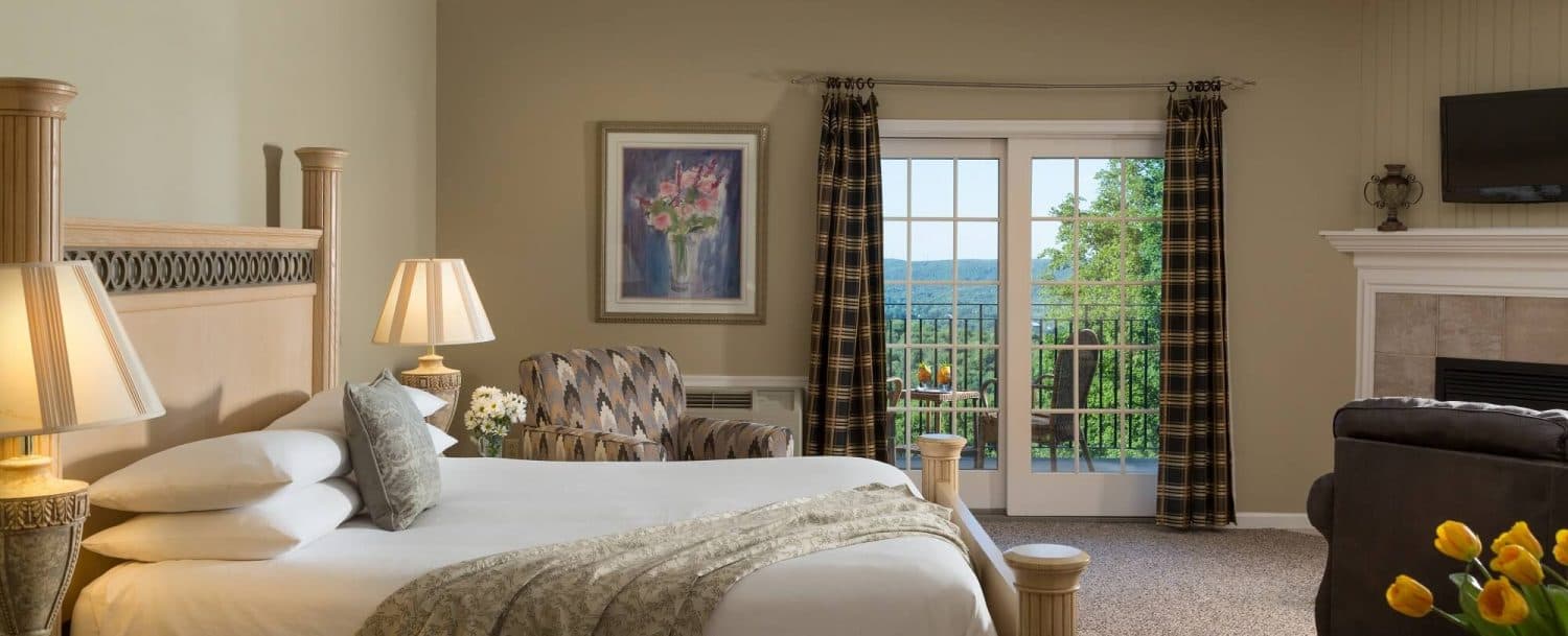A cozy hotel room featuring a large bed, a seating area, and doors opening to a scenic view.