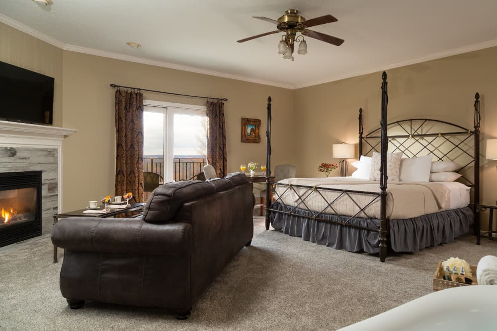 Bedroom, ceiling fan, metal bed, fireplace, tan walls, white bedding