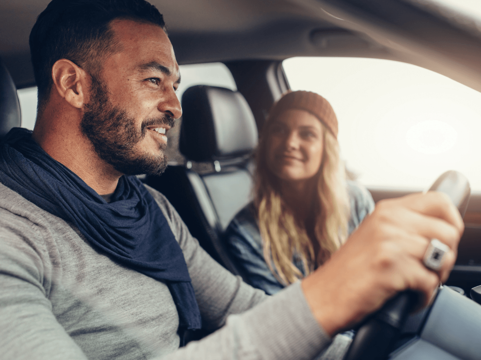A man and a woman smile at each other while sitting in a car. A man and a woman smile at each other while sitting in a car.