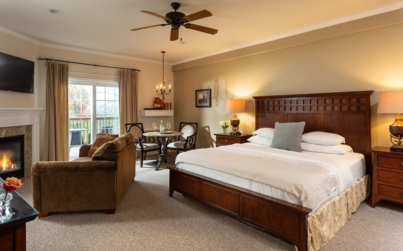 A cozy bedroom featuring a king-sized bed, seating area, dining table, and a balcony.