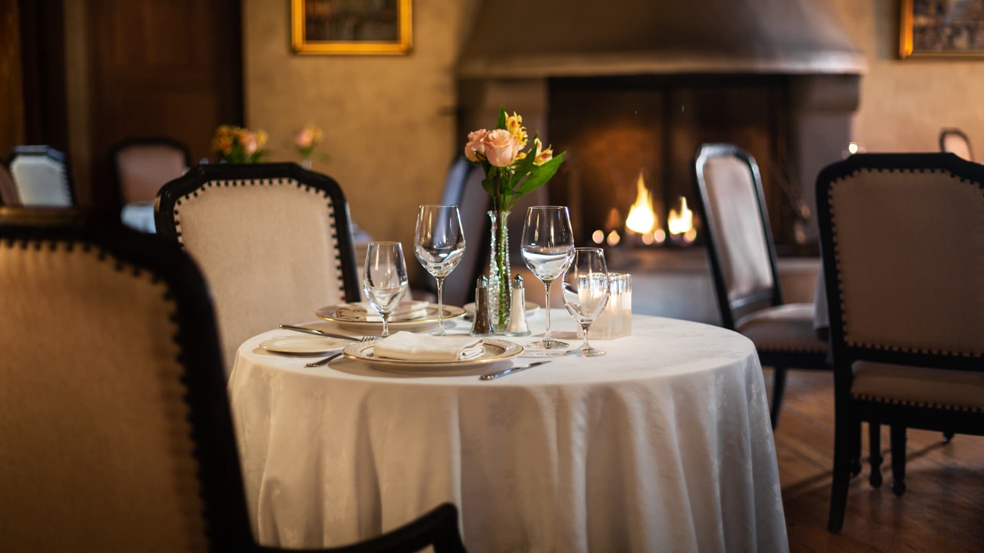 Formal dining in front of fireplace white table cloth and china and crystal settings