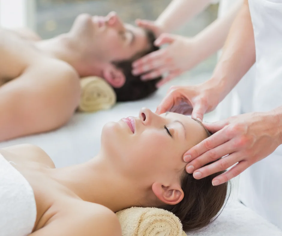 A woman receives a facial massage while a man lies nearby, both relaxing in a spa setting.