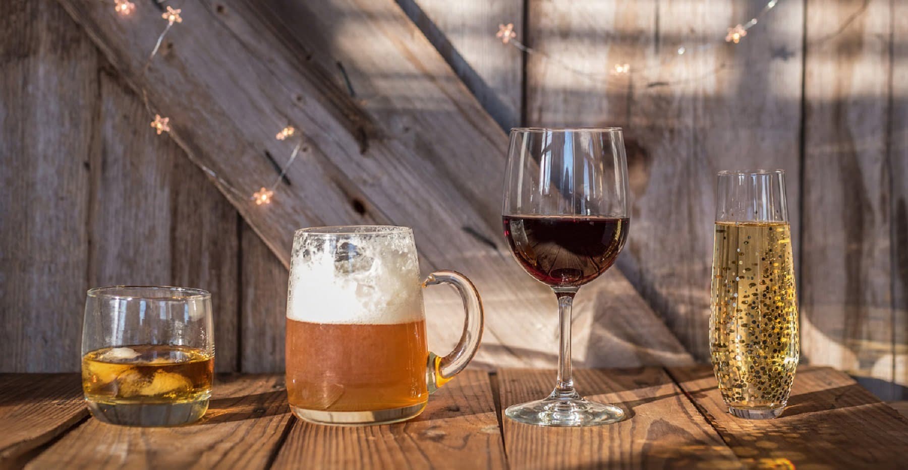 Four different alcoholic beverages arranged on a wooden table against a rustic background.