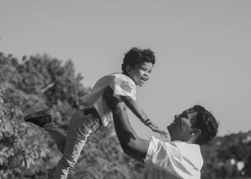 A man lifts a joyful child into the air against a natural backdrop. A man lifts a joyful child into the air against a natural backdrop.