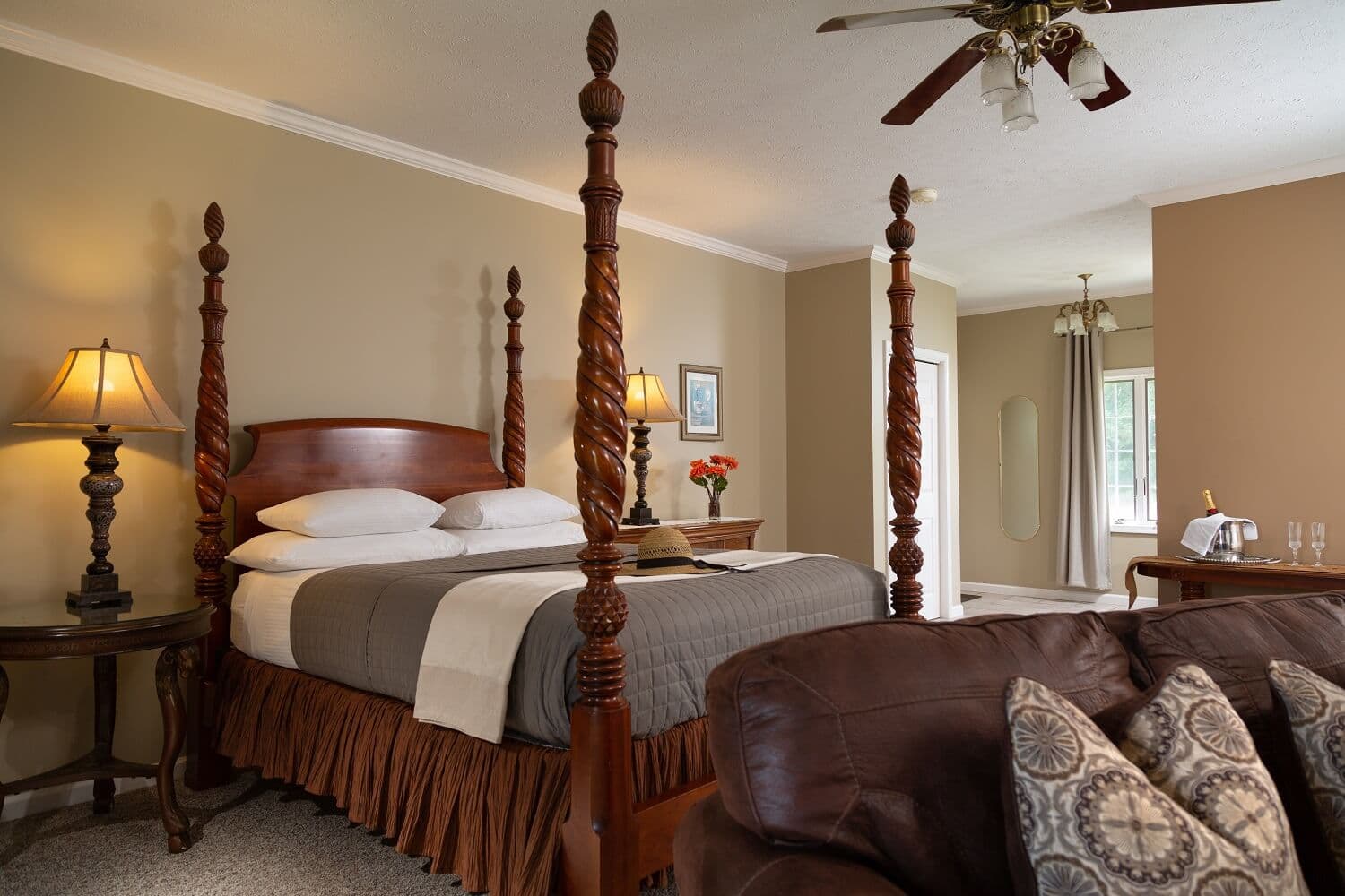 A cozy bedroom featuring a four-poster bed, warm lighting, and a comfortable seating area.