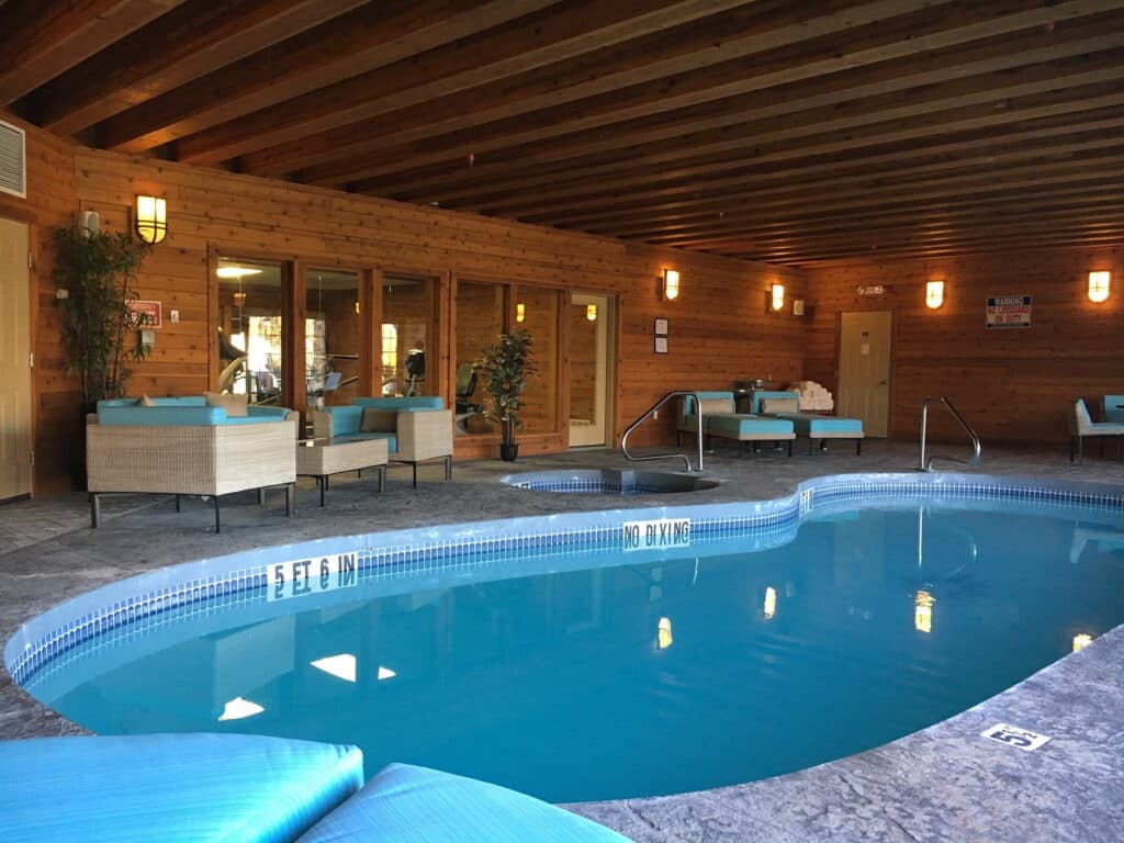 Indoor pool area featuring turquoise seating and wooden walls.