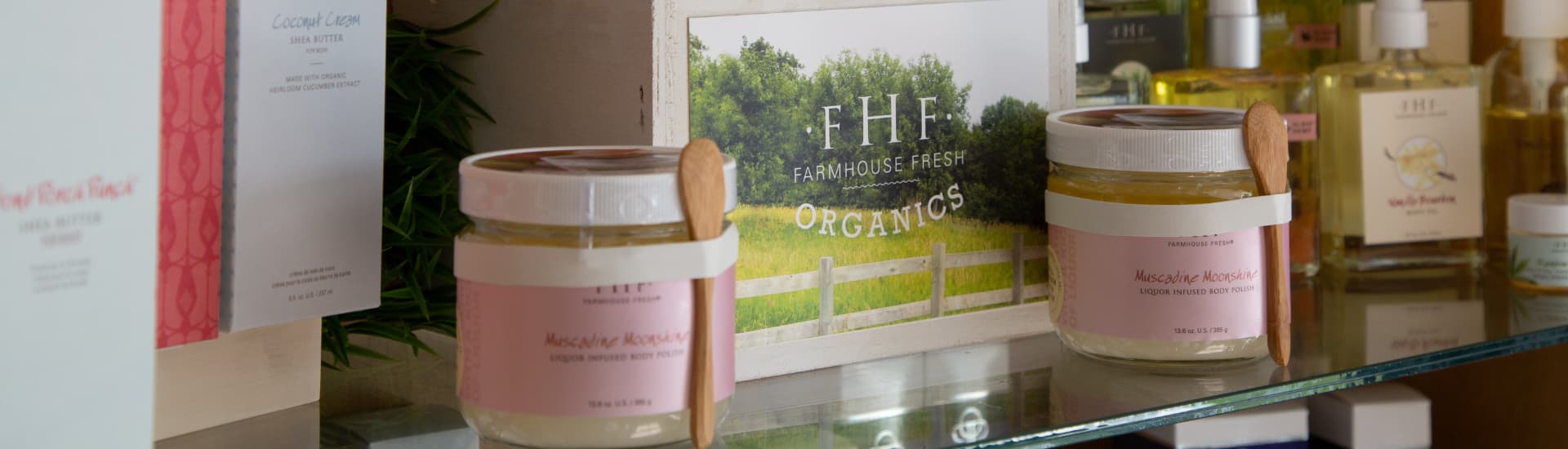 A close-up of Farmhouse Fresh skincare products, including a jar of body butter with a wooden spoon.