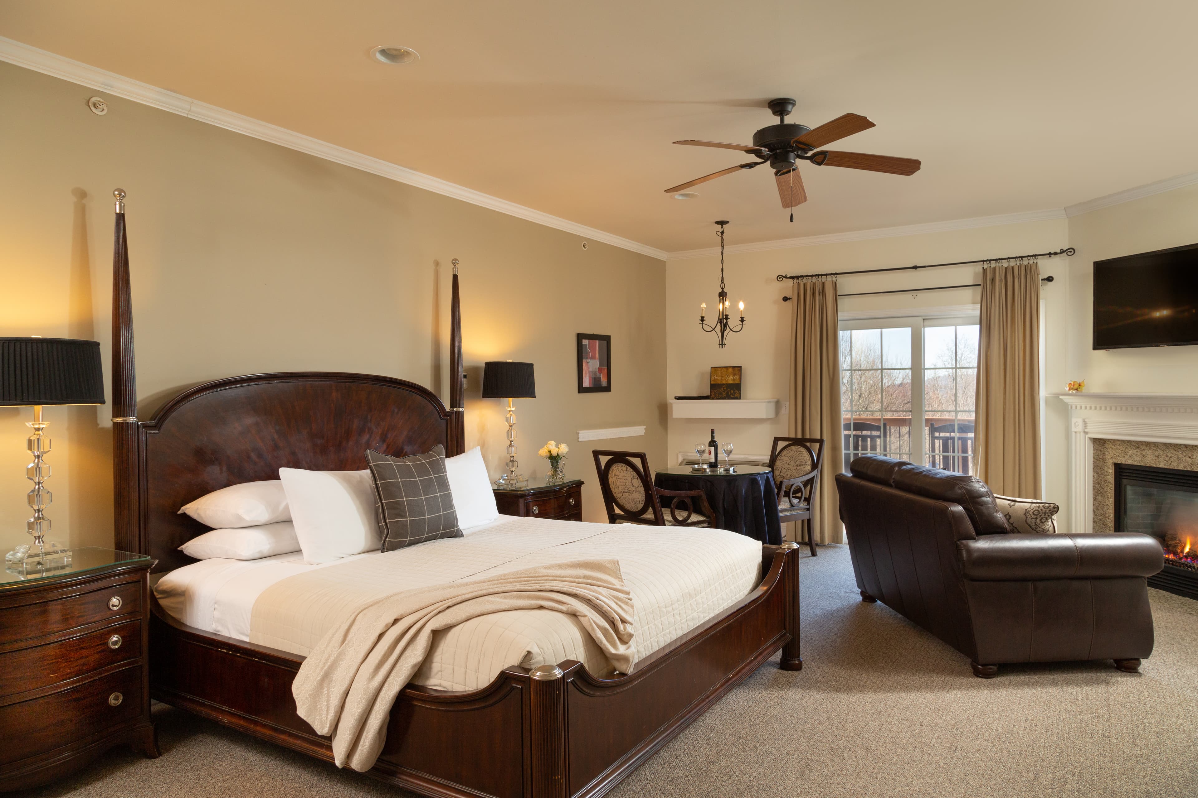 A cozy bedroom featuring a wooden bed, seating area, and a fireplace.