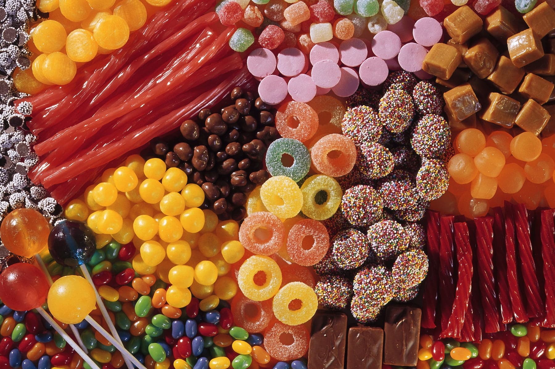 A colorful assortment of various candies, including gummies, chocolates, lollipops, and licorice. A colorful assortment of various candies, including gummies, chocolates, lollipops, and licorice.