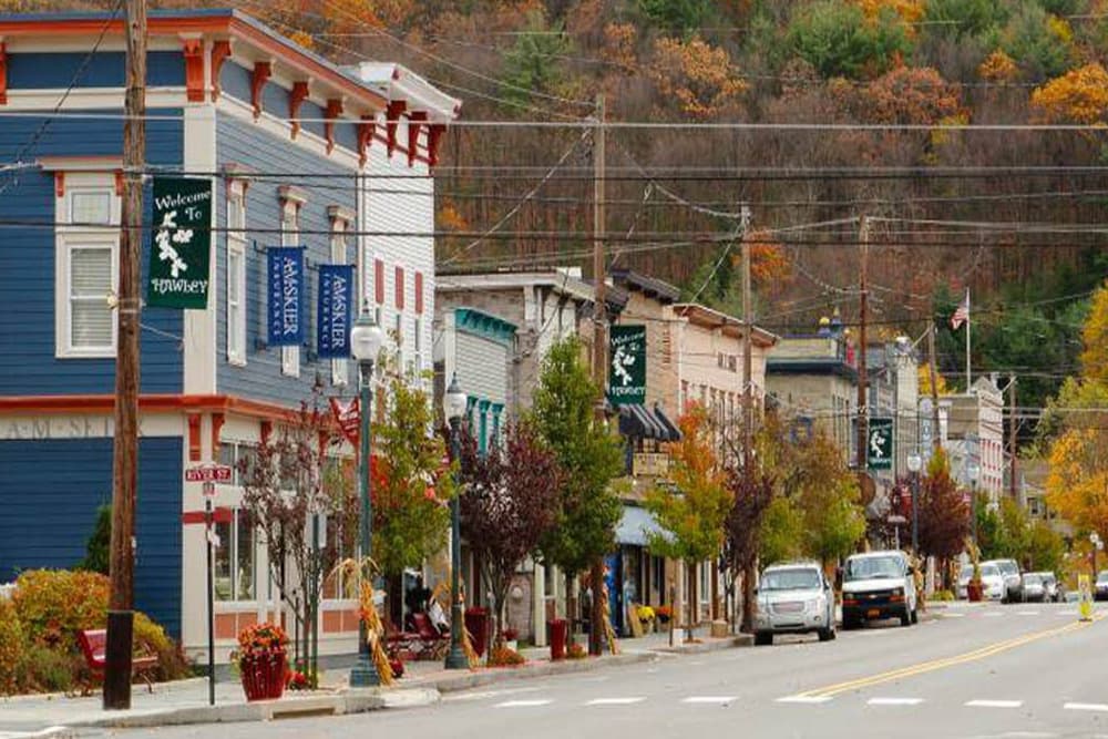 A picturesque street scene in Hawley, Pennsylvania, with colorful buildings and fall foliage.