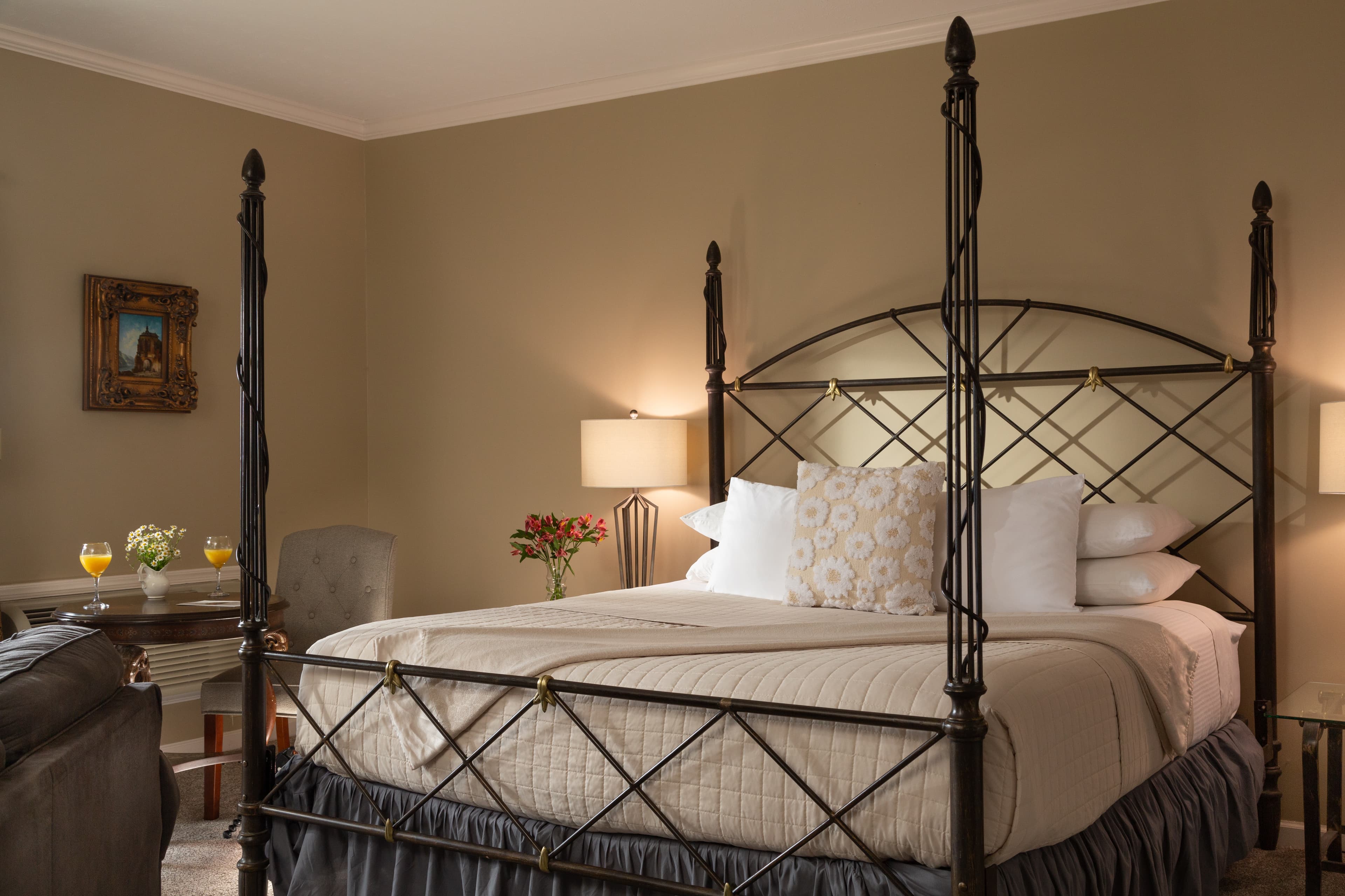 A beautifully styled bedroom featuring a wrought-iron canopy bed, soft bedding, and tasteful decor.