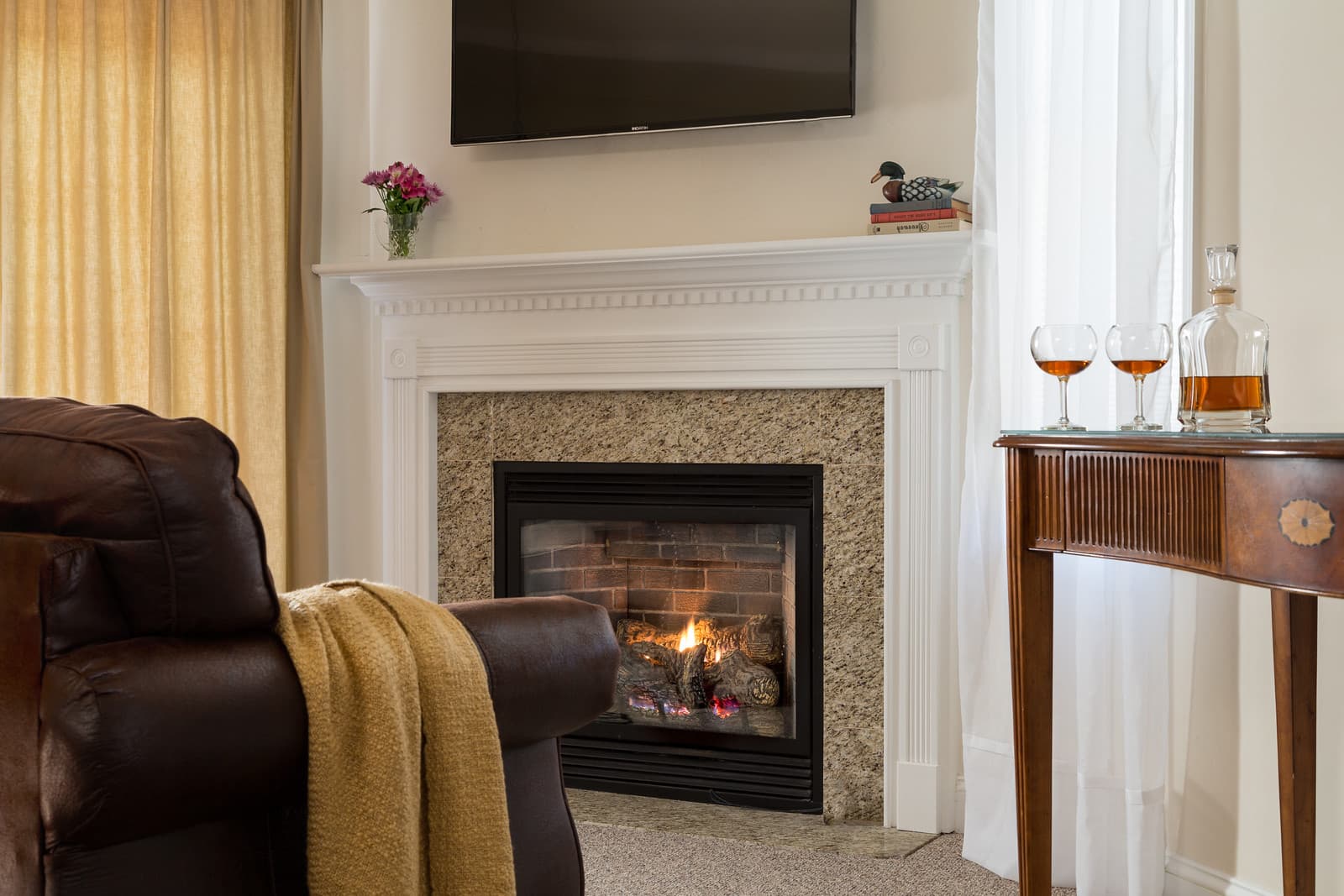 Cozy living room featuring a fireplace, a TV, and a side table with drinks.