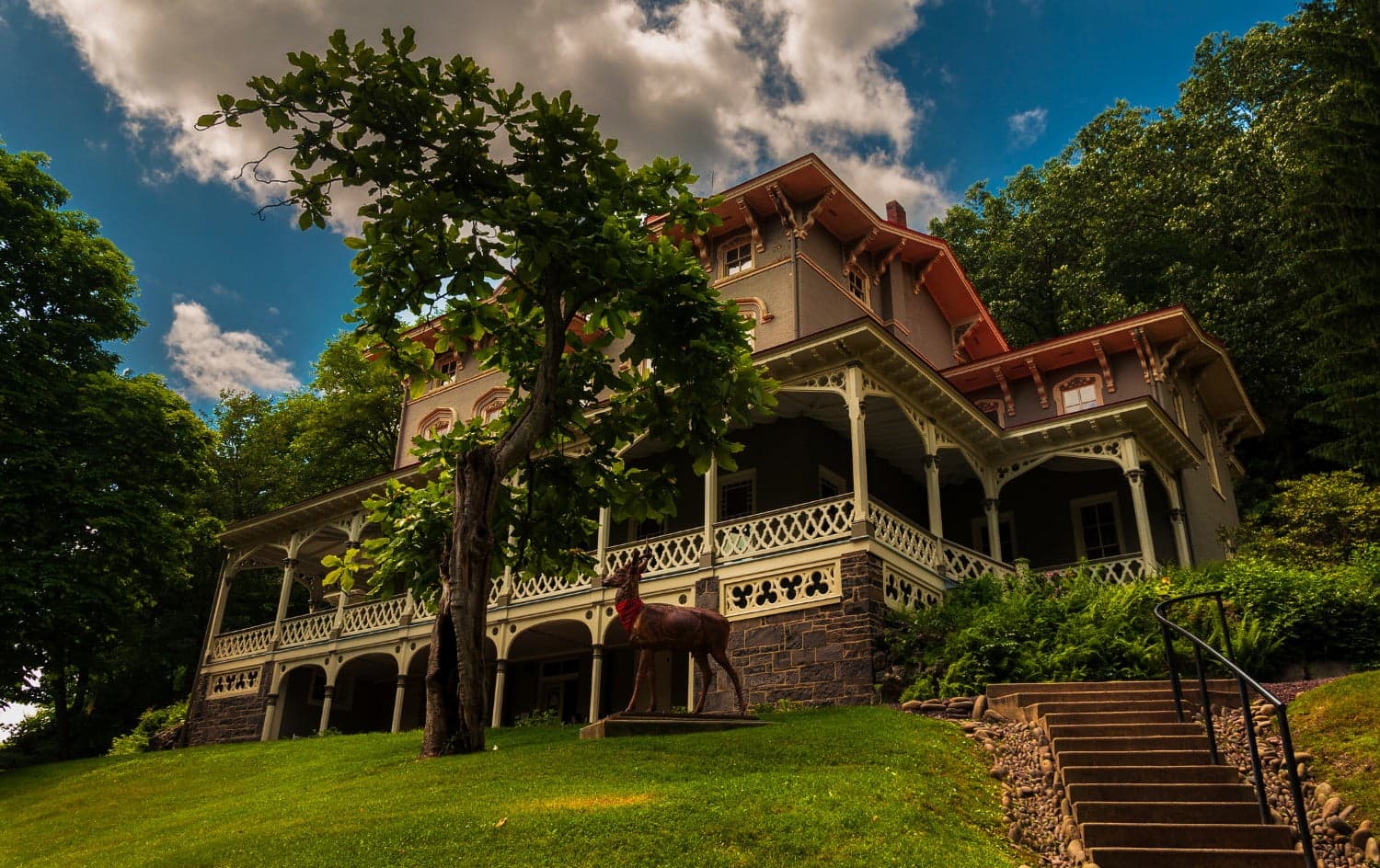 A historic mansion with intricate architectural details, surrounded by greenery and a sculpture of a horse. A historic mansion with intricate architectural details, surrounded by greenery and a sculpture of a horse.