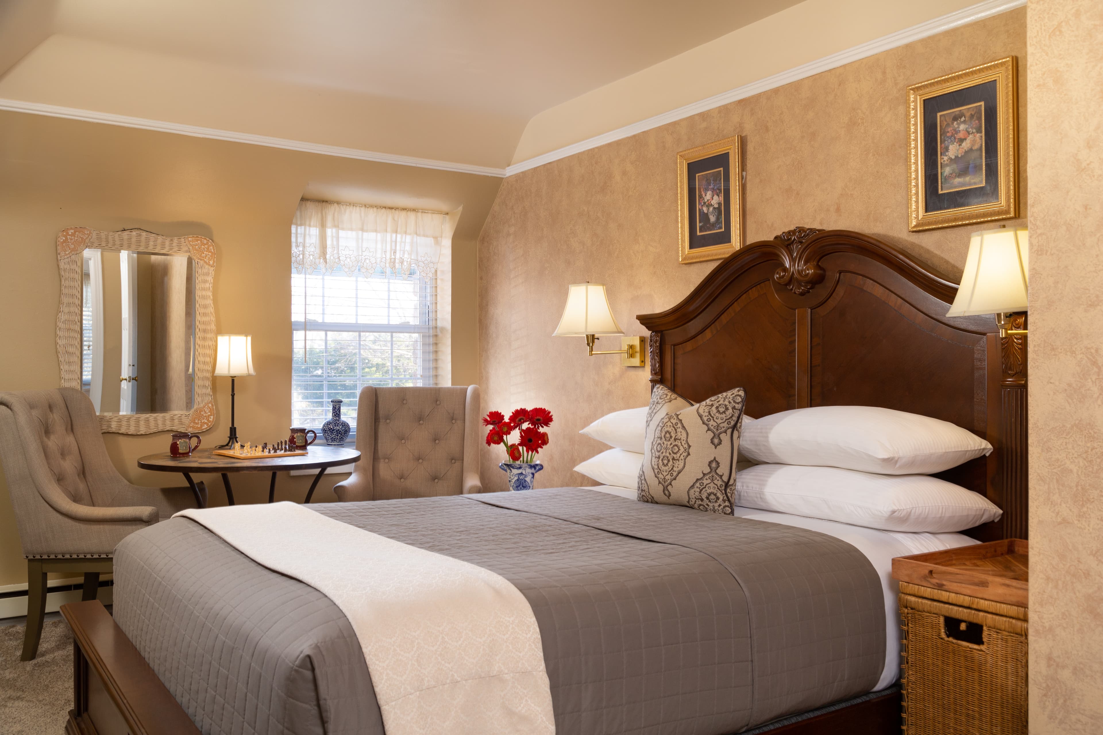 A cozy bedroom featuring a large bed, elegant decor, and a small dining table with chairs.
