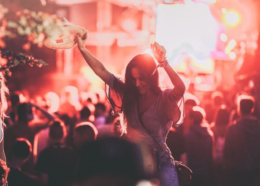 A woman joyfully dances with her arms raised at a vibrant music festival. A woman joyfully dances with her arms raised at a vibrant music festival.