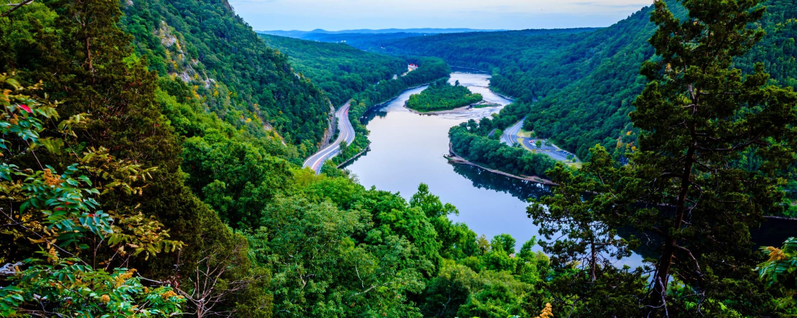 A serene river winding through lush green mountains under a blue sky. A serene river winding through lush green mountains under a blue sky.