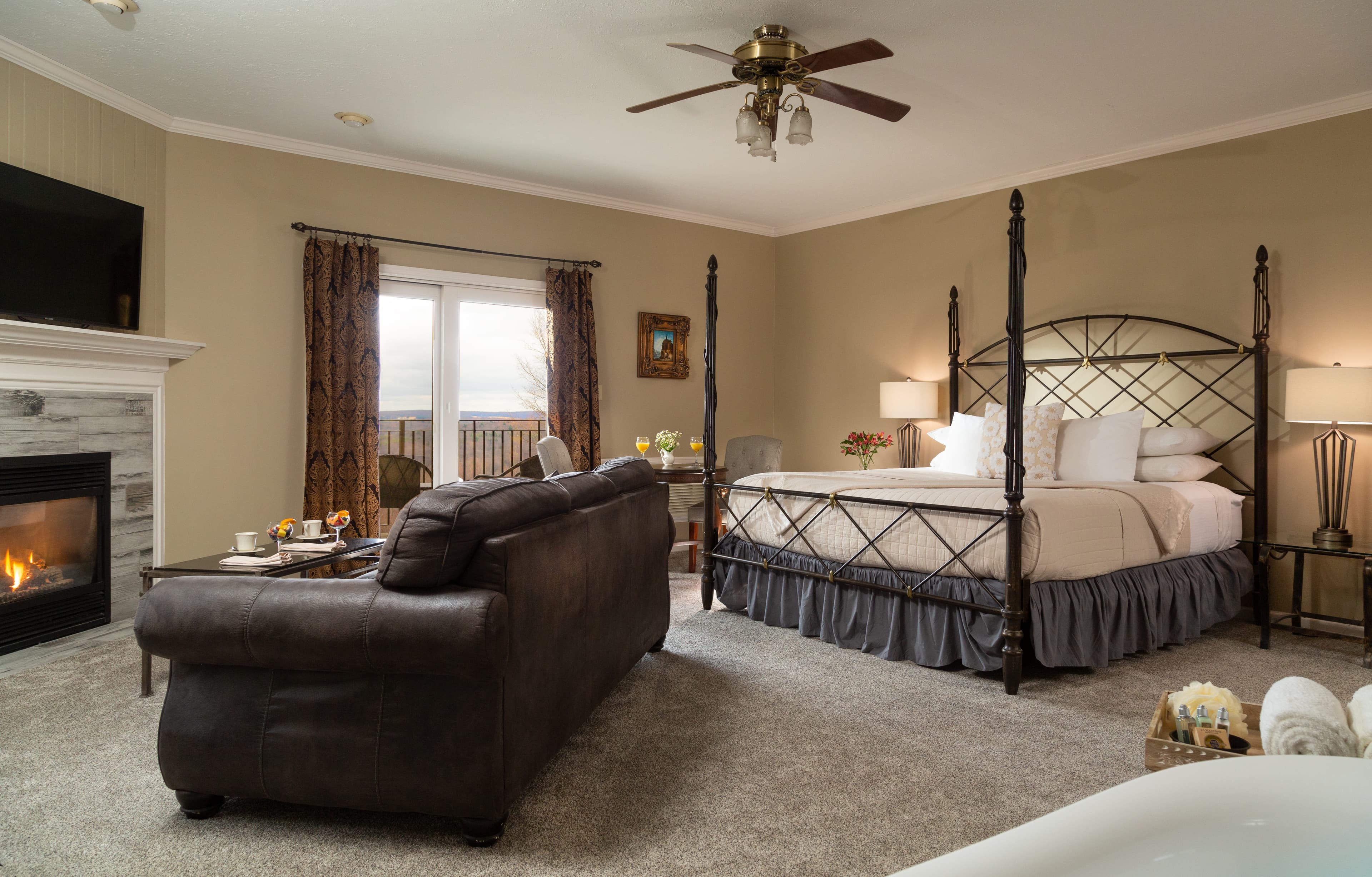 A cozy hotel room featuring a queen-sized bed, a seating area, and a fireplace.
