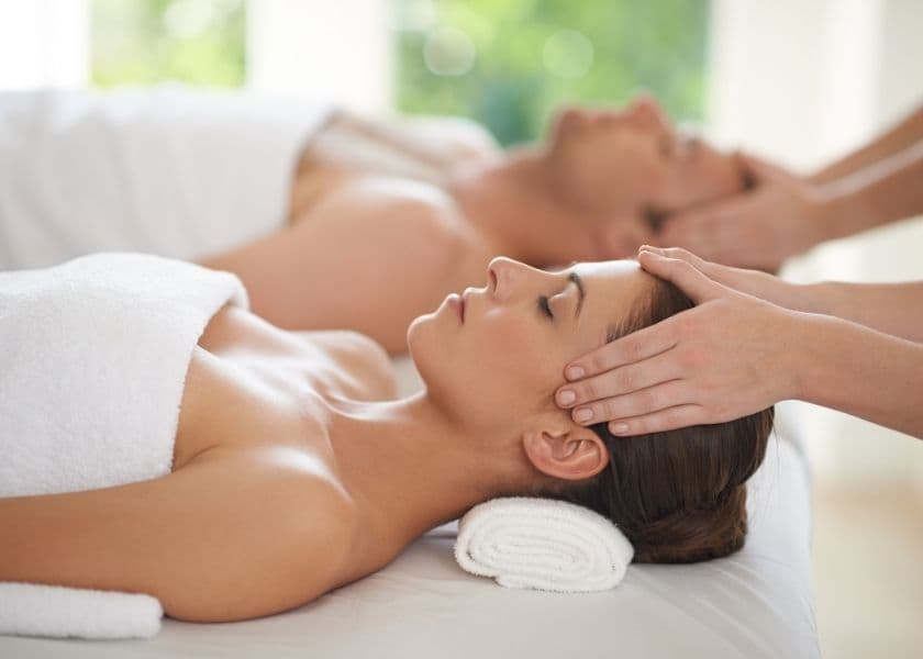 A woman receives a relaxing massage while a man lies beside her on a treatment table. A woman receives a relaxing massage while a man lies beside her on a treatment table.
