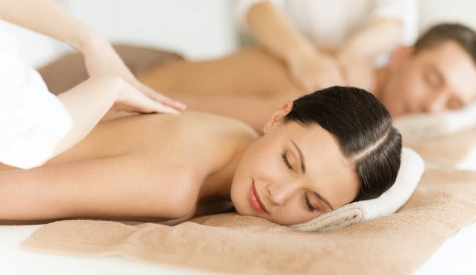 A man and woman lying face down on massage tables getting back massages.